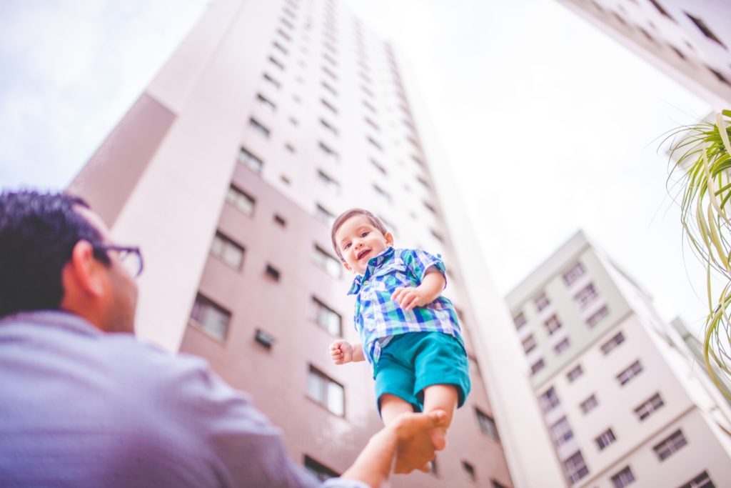 father holding a baby with buildings in background