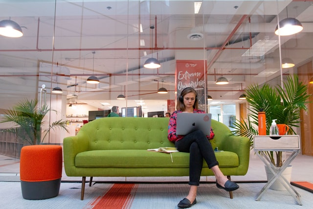 woman sitting on a green couch while working