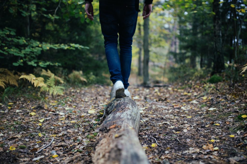 walking in the woods and hiking outdoors, photo of man's legs wearing jeans and white sneakers