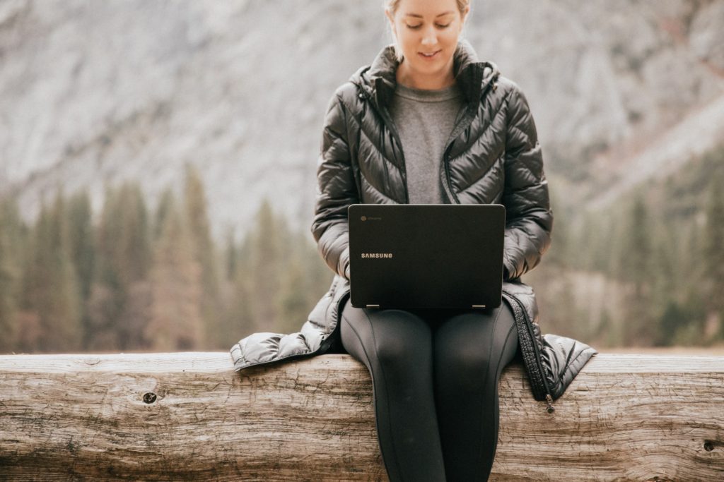 woman working on her laptop outdoors in the woods with nature, remote work