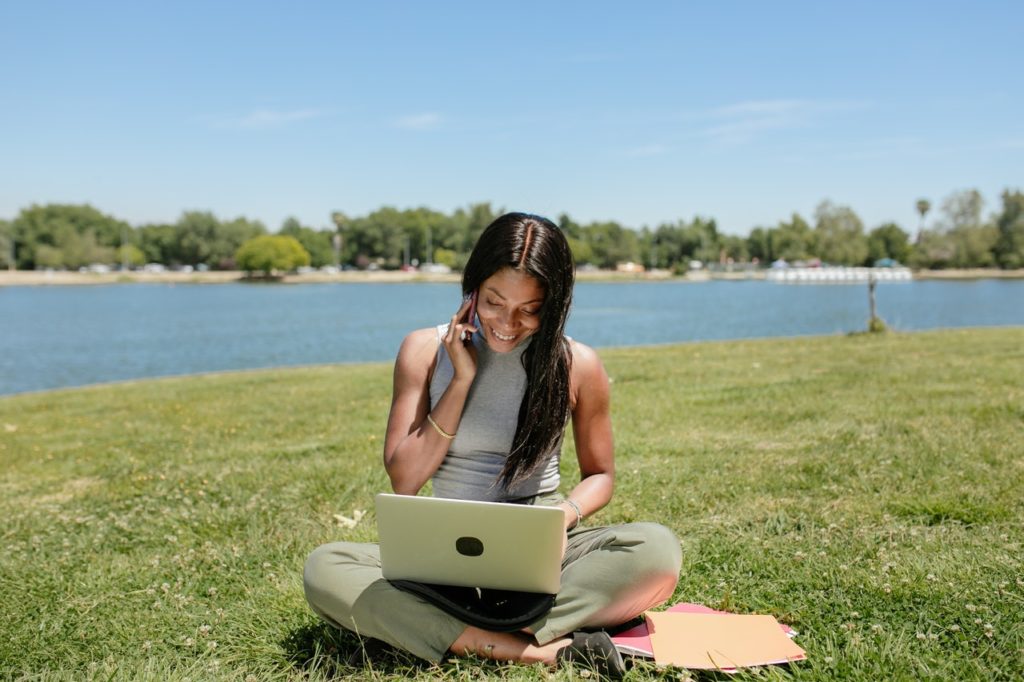 business woman working in the park by the lake with her laptop and phone in the middle of the day