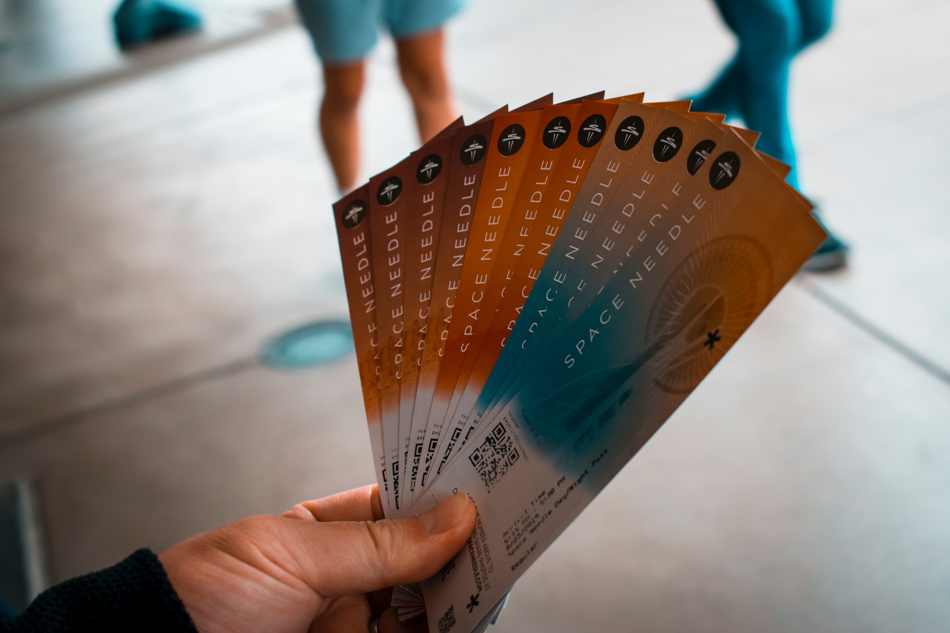 Person's hand holding a fan of multiple event tickets