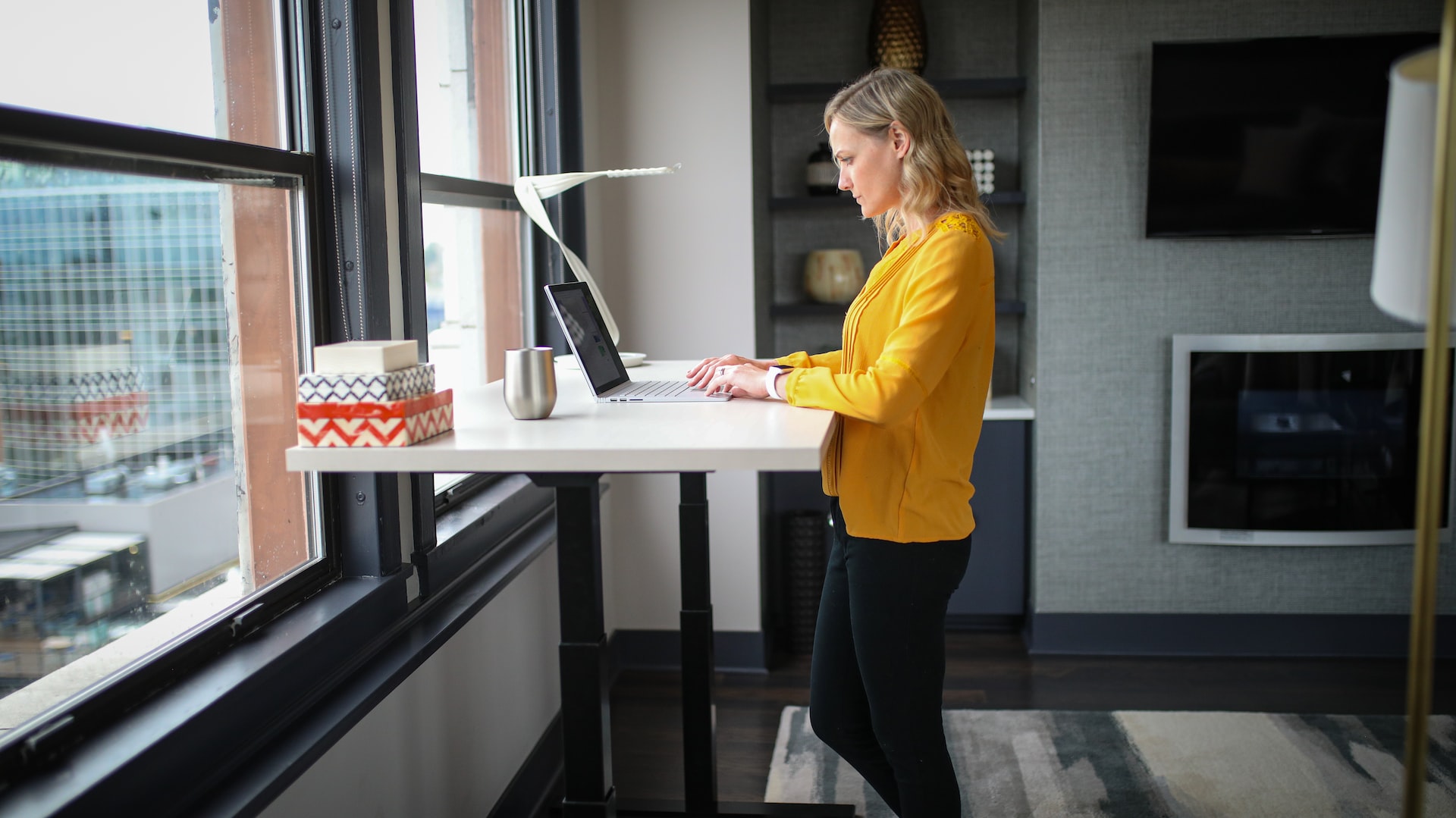 Woman standing at a standing desk next to the window