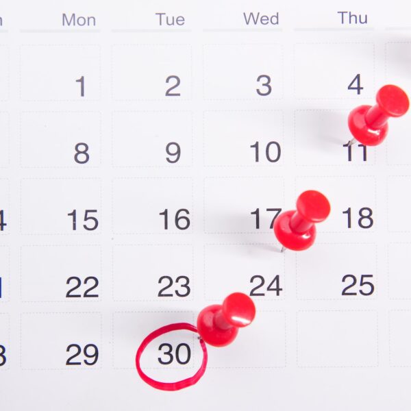 A calendar with red pins on one day in each week