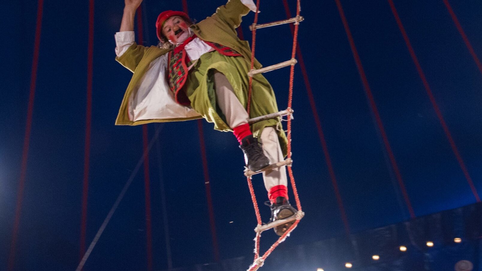 A circus performer climbing a suspended staircase