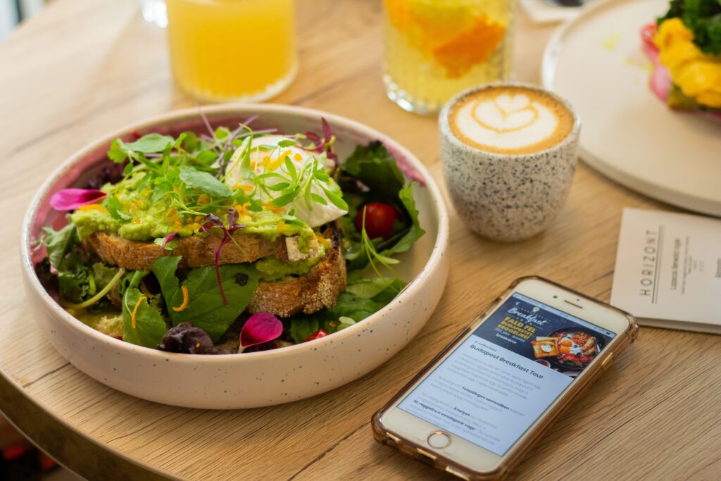A healthy lunch bowl, latte, and phone on a table