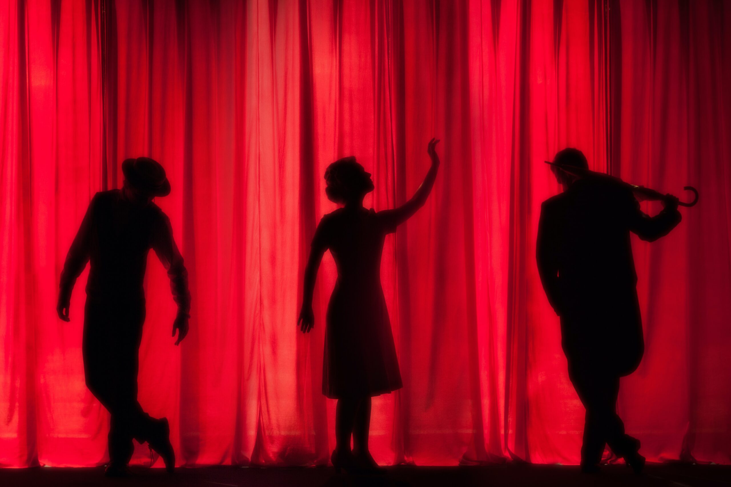Performers in front of a red curtain