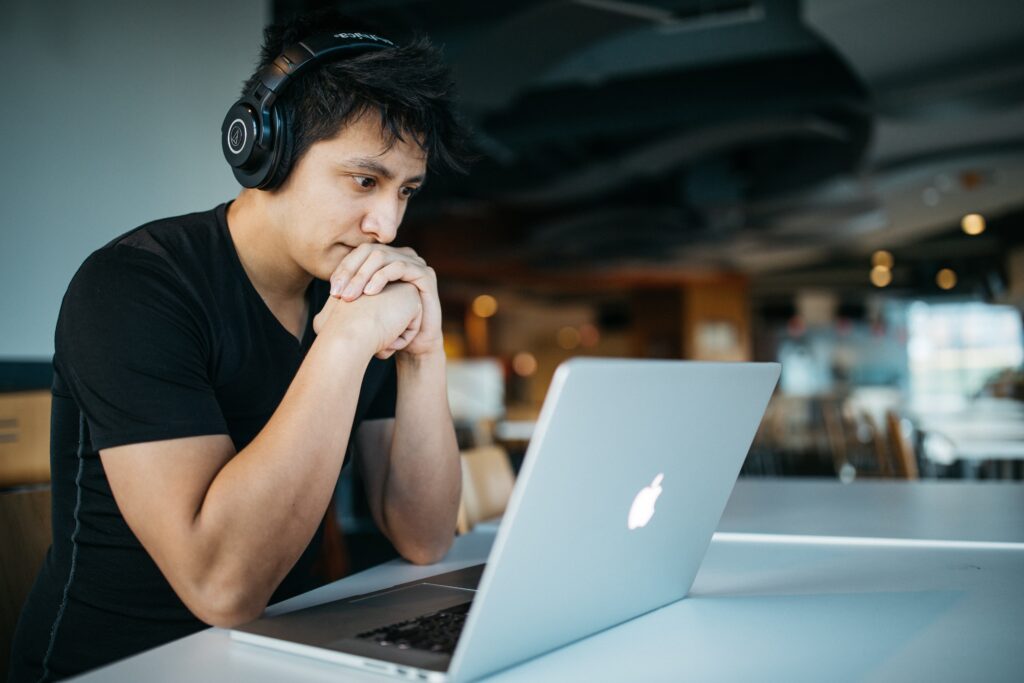 Man concentrating while wearing headphones and looking at computer screen