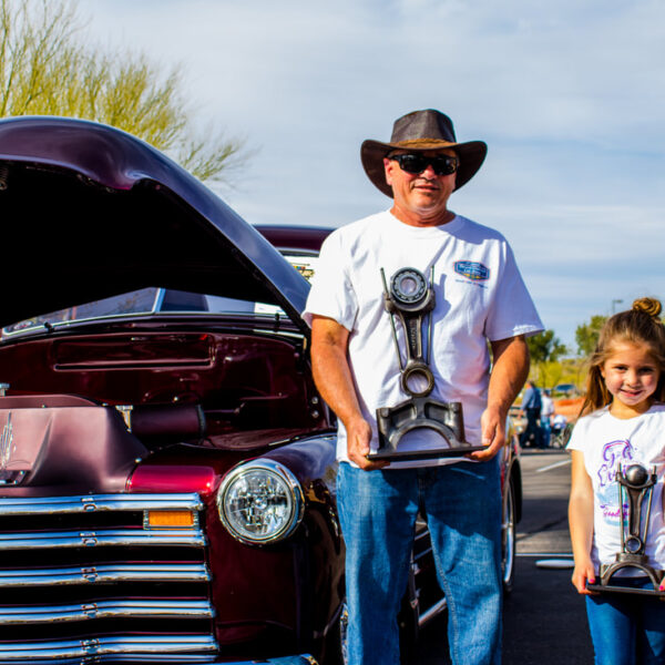 A man and child standing in front of a classic car