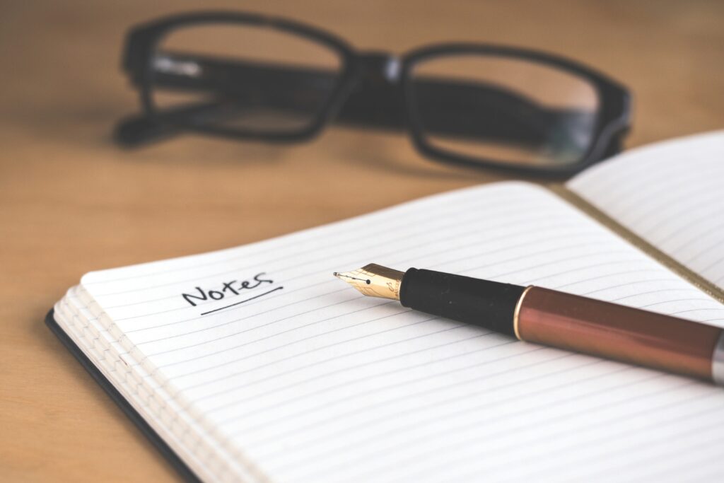 Notepaper that says "notes" with a pen and glasses close by